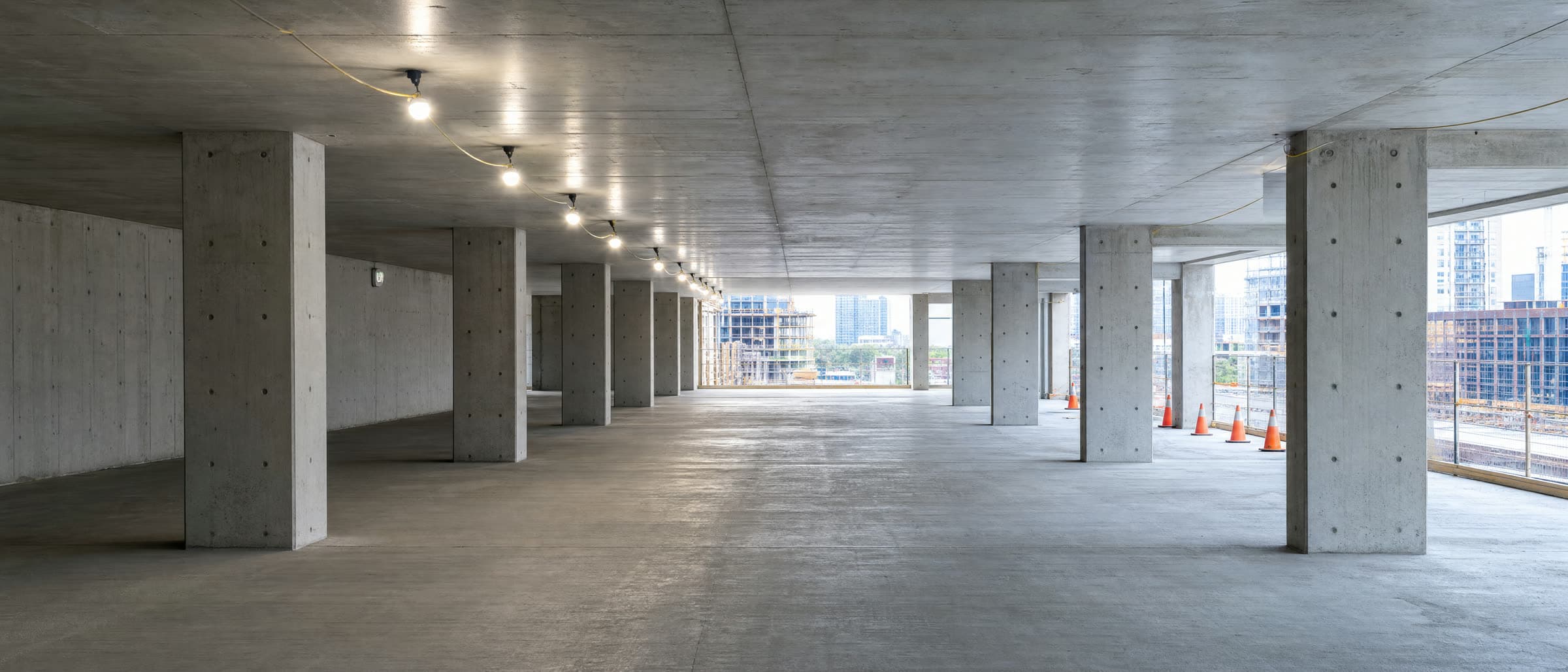 A finished concrete floor plate in a high-rise under construction, columns running to the open edge